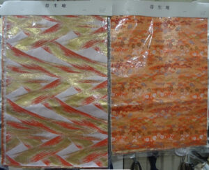 Two pieces of orange, gold and red fabric with abstract patterns