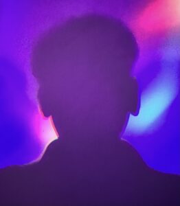 Pink, blue and grey psychedelic outline of a man's head and shoulders with bright lights around it
